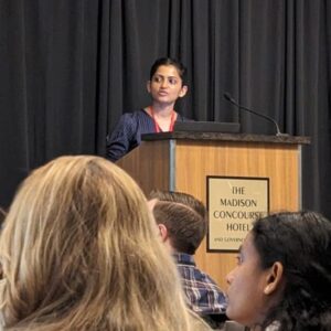 A speaker standing at a podium whilst audience members look on